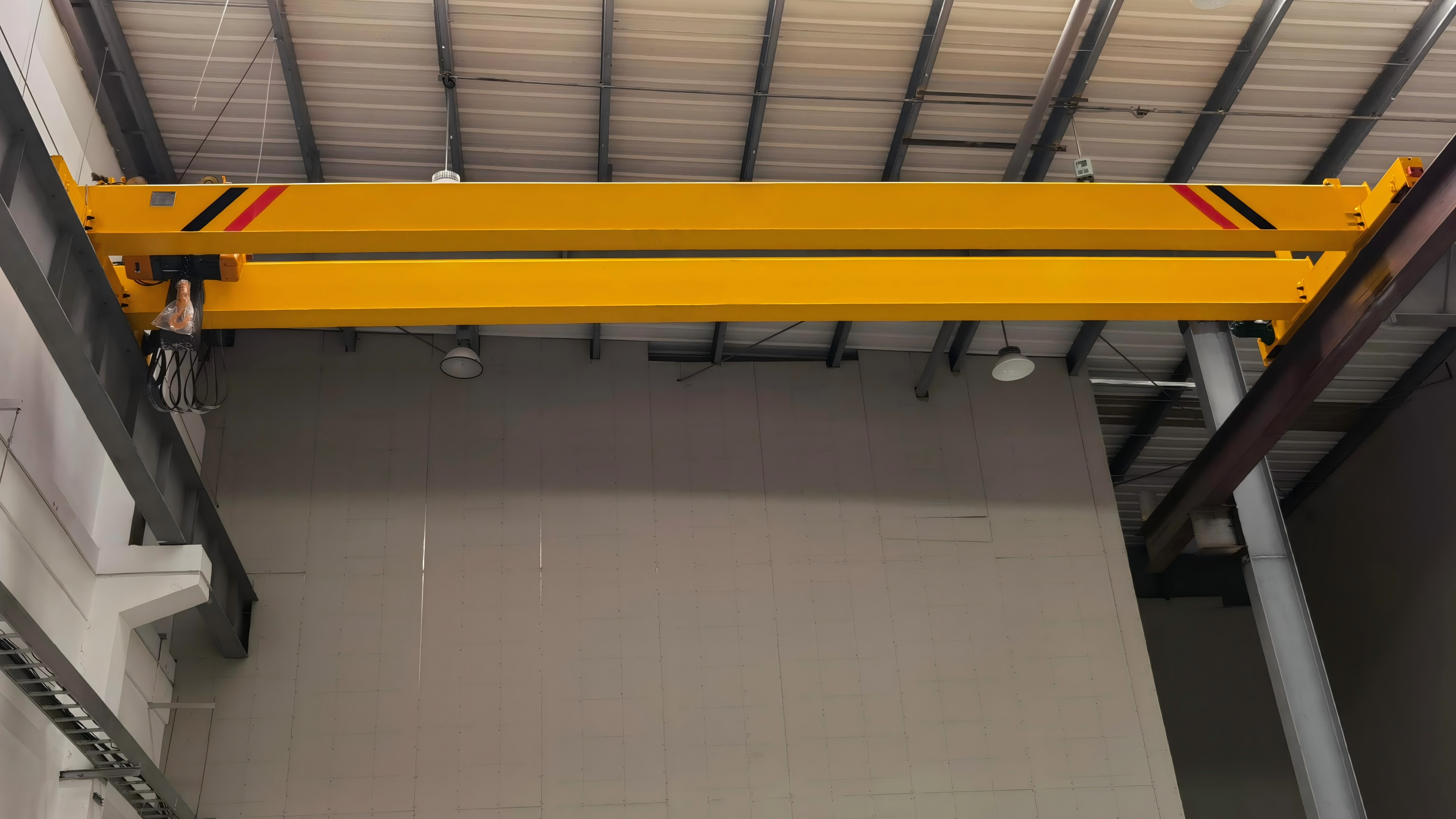 Yellow bridge crane installed across elevated runway beams in an industrial building