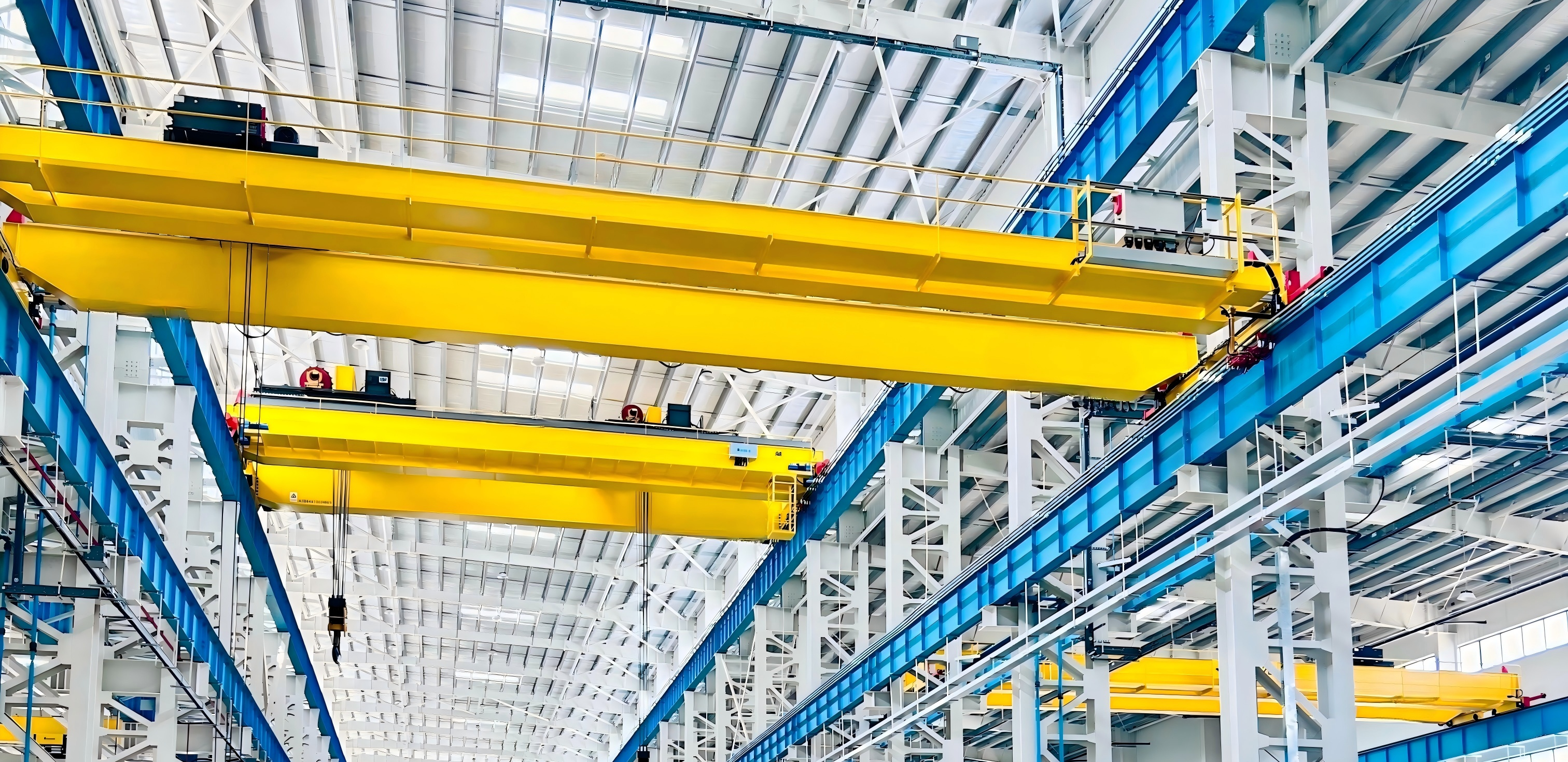 Yellow double girder bridge cranes in a bright industrial workshop